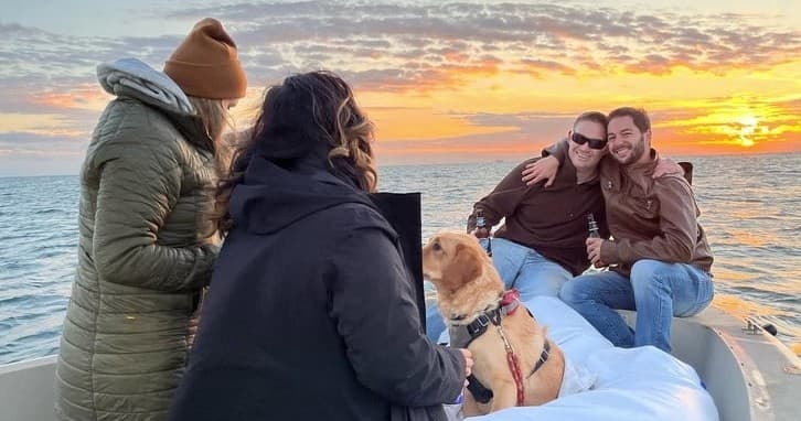 Friends and dog enjoying sunset cruise on open coastal waters