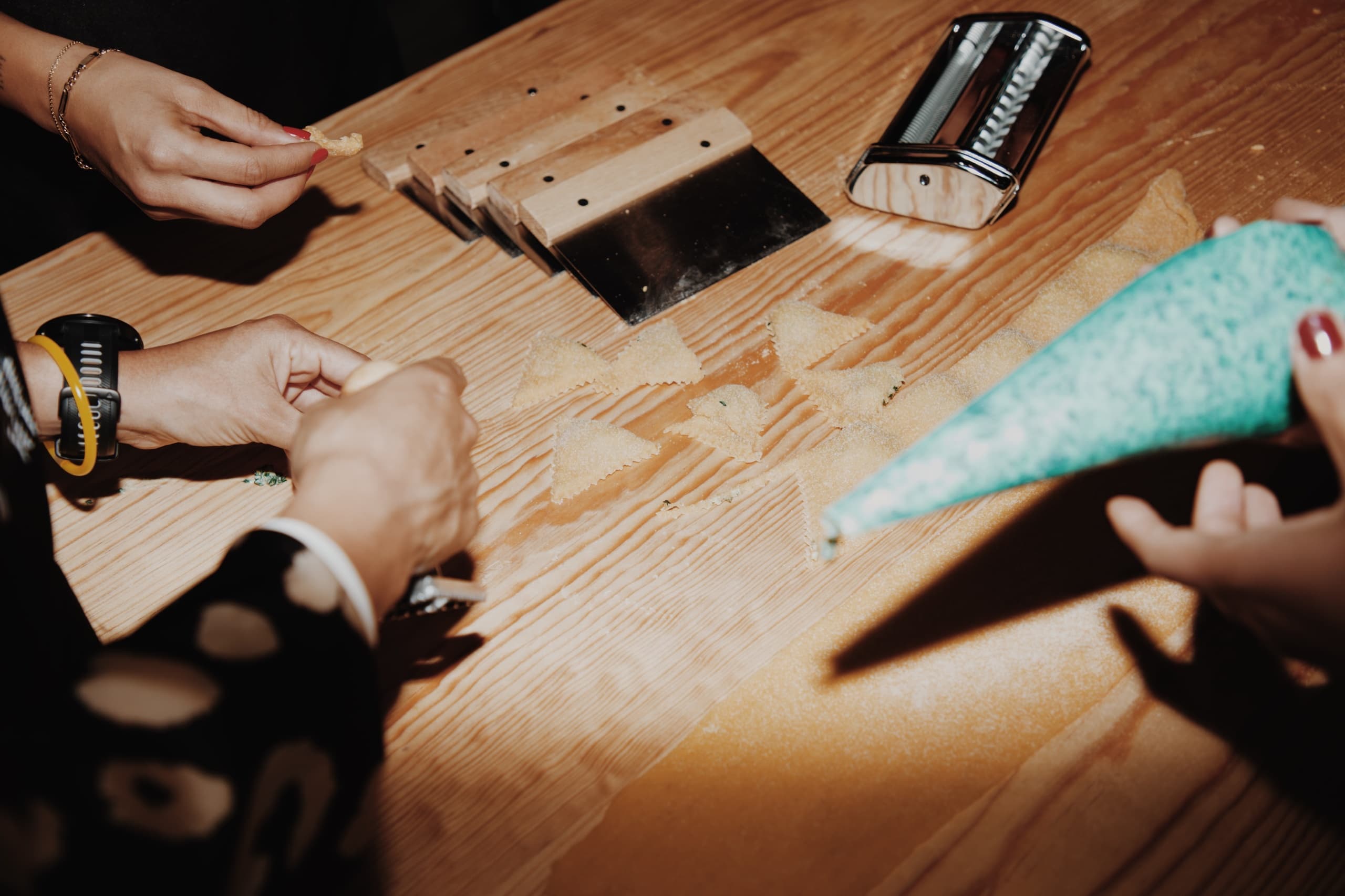 Hands preparing pasta dough on wooden board in kitchen