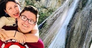 Couple posing by waterfall in canyon, scenic outdoor activity