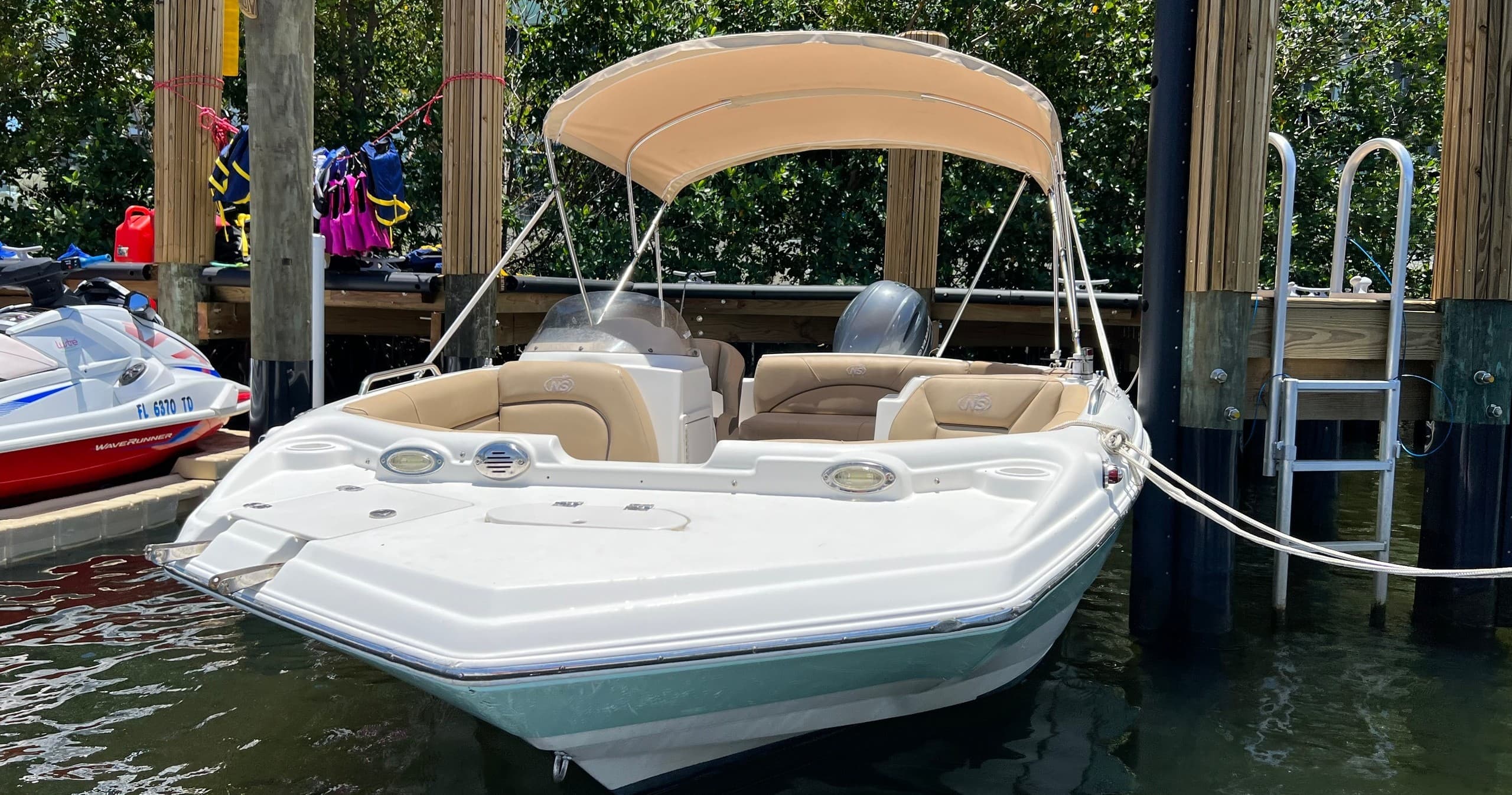 White motorboat moored at marina dock with seating and canopy