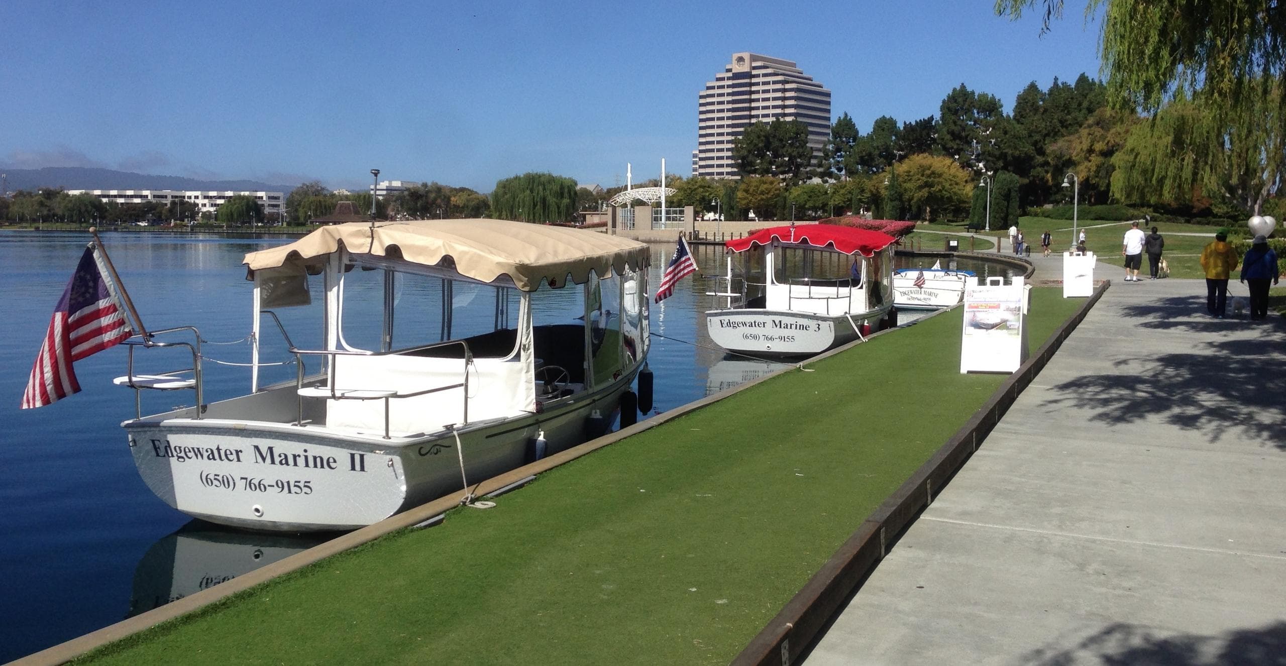 Lakeside dock with lined tour boats and clear blue sky panorama