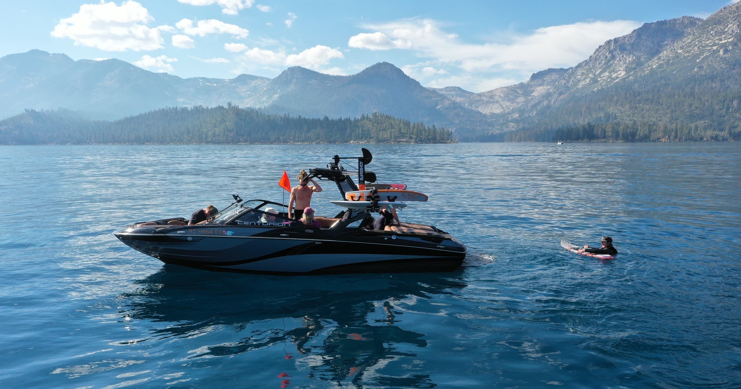 Wakeboarding boat on Sierra mountain lake with riders and clear water