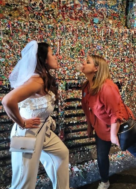 Bride and friend at famous gum wall alley posing and laughing
