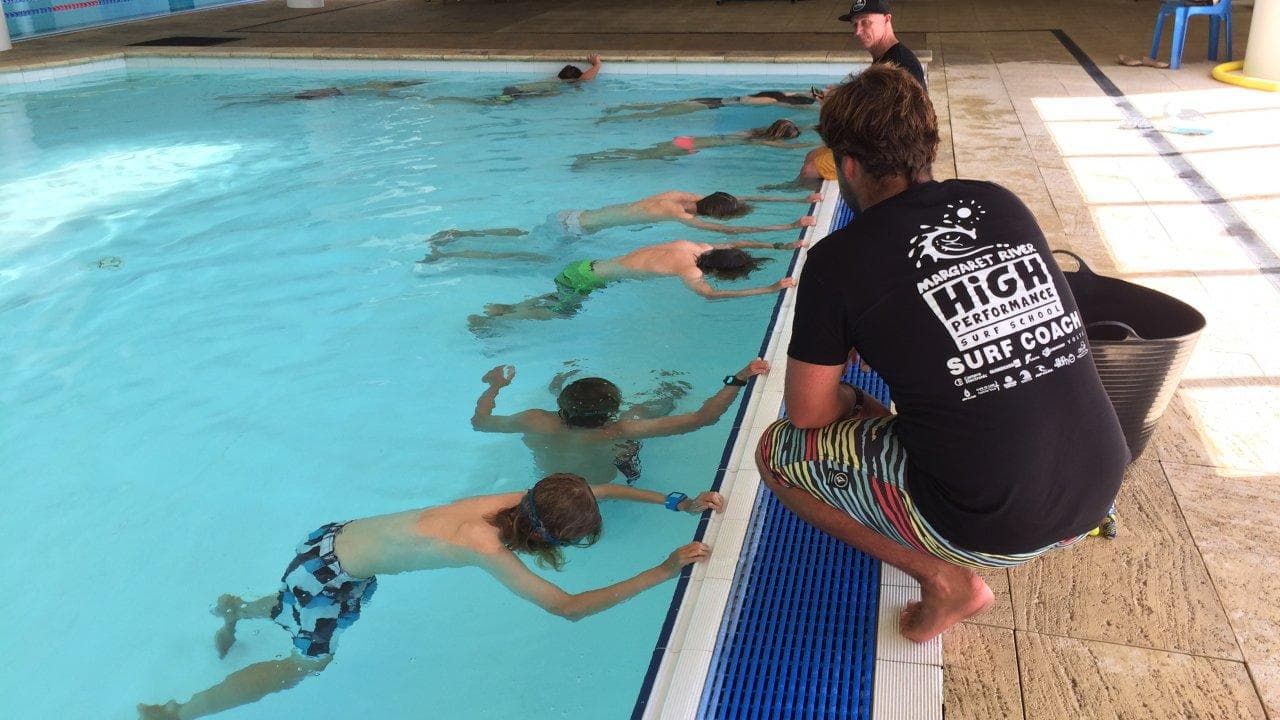 Surf instructor coaching children in indoor pool surf training