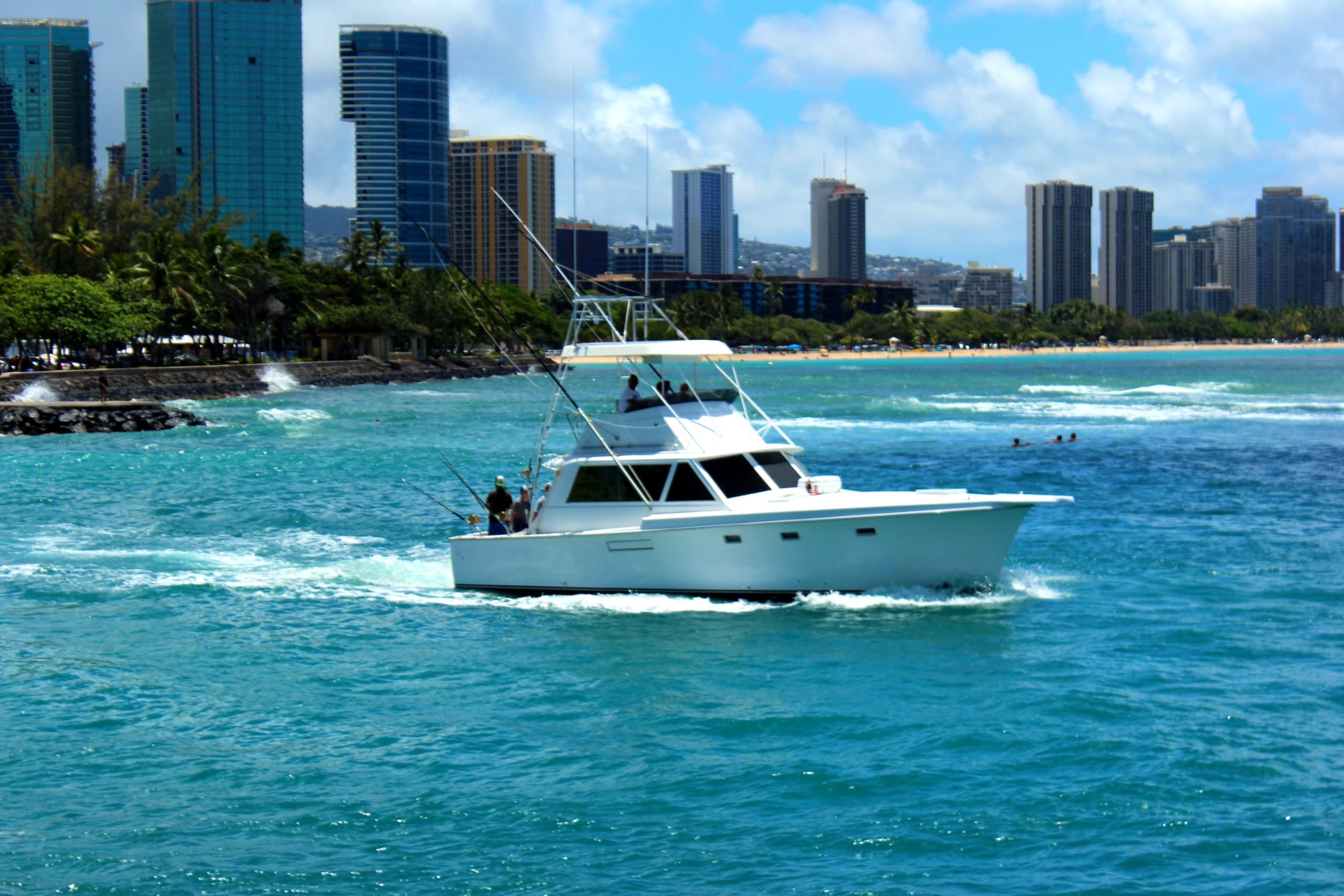 Sportfishing boat cruising near Waikiki skyline on turquoise ocean