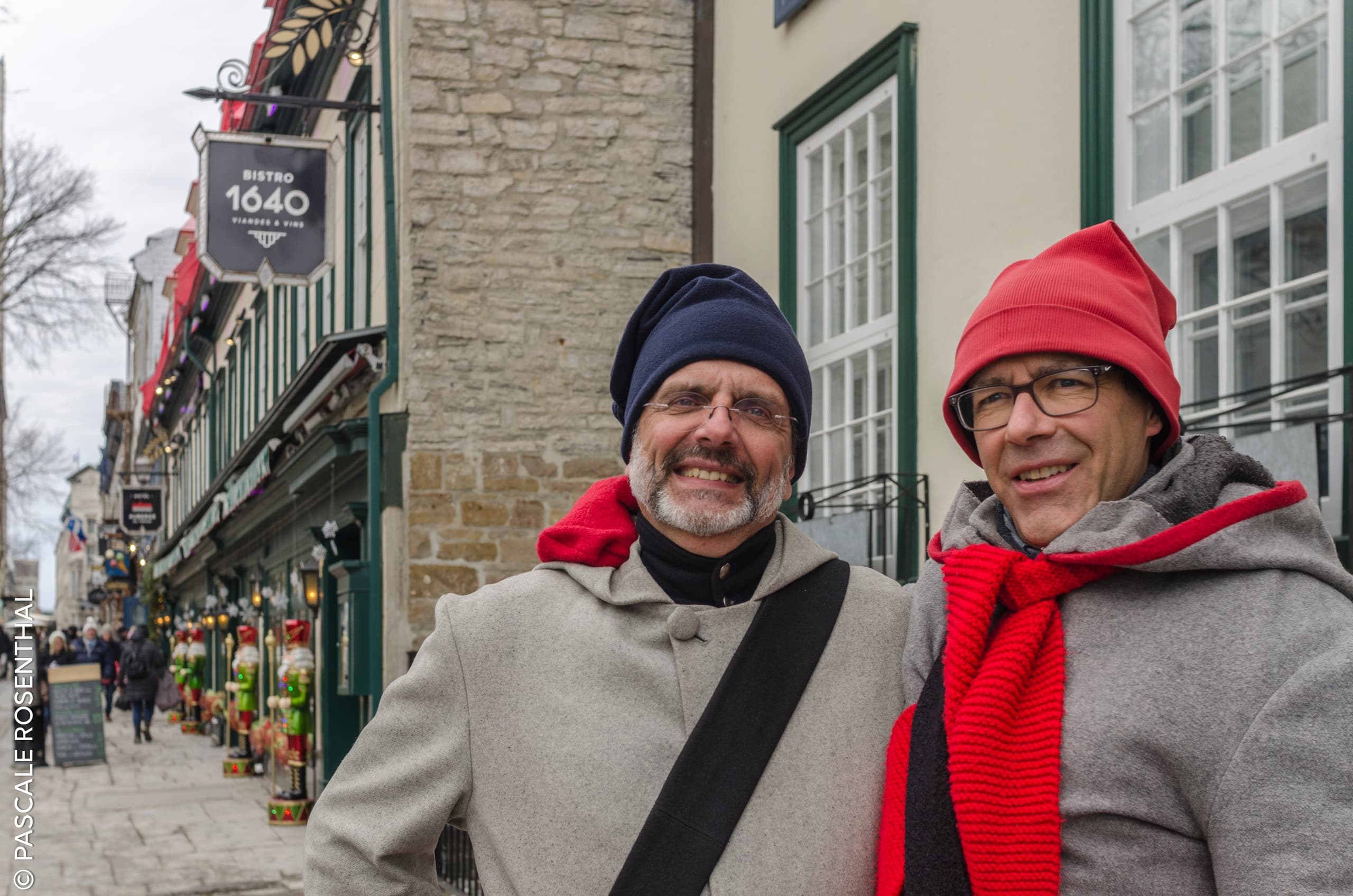 Smiling winter tourists strolling quaint old-town street with shops