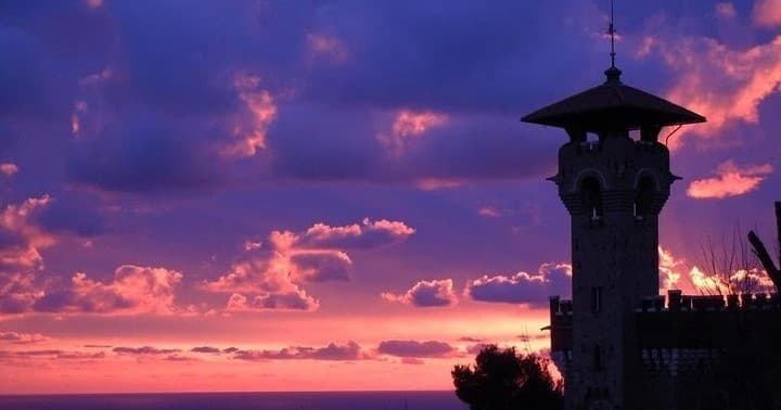 Sunset coastal watchtower silhouetted over dramatic ocean horizon