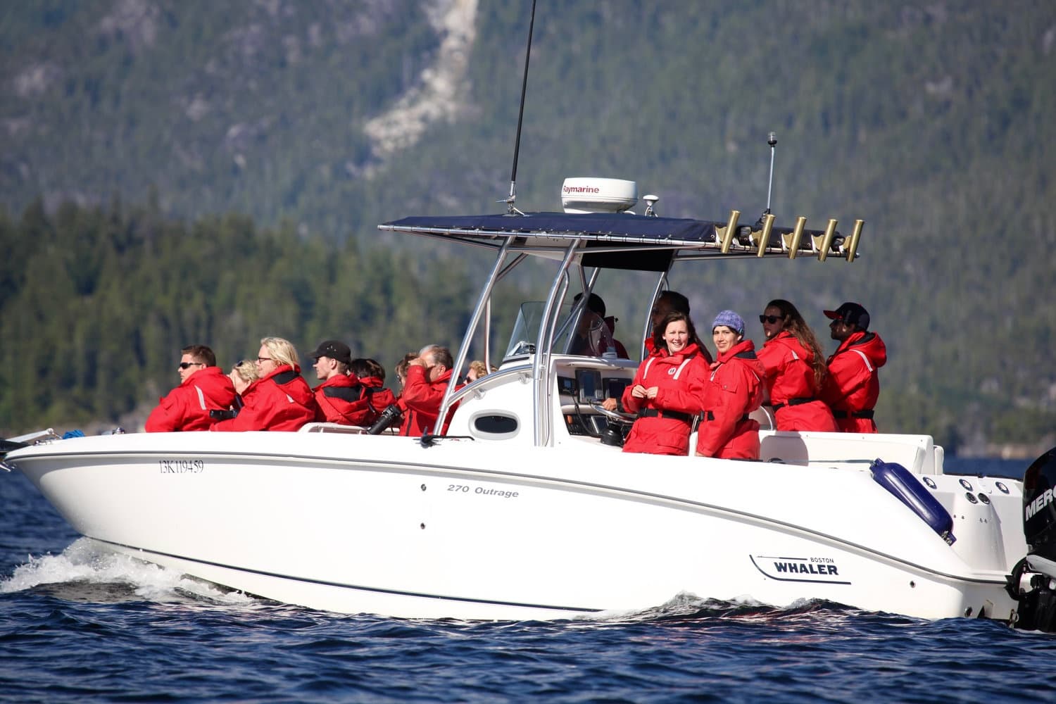White whale-watching boat with guests in red jackets on open ocean trip