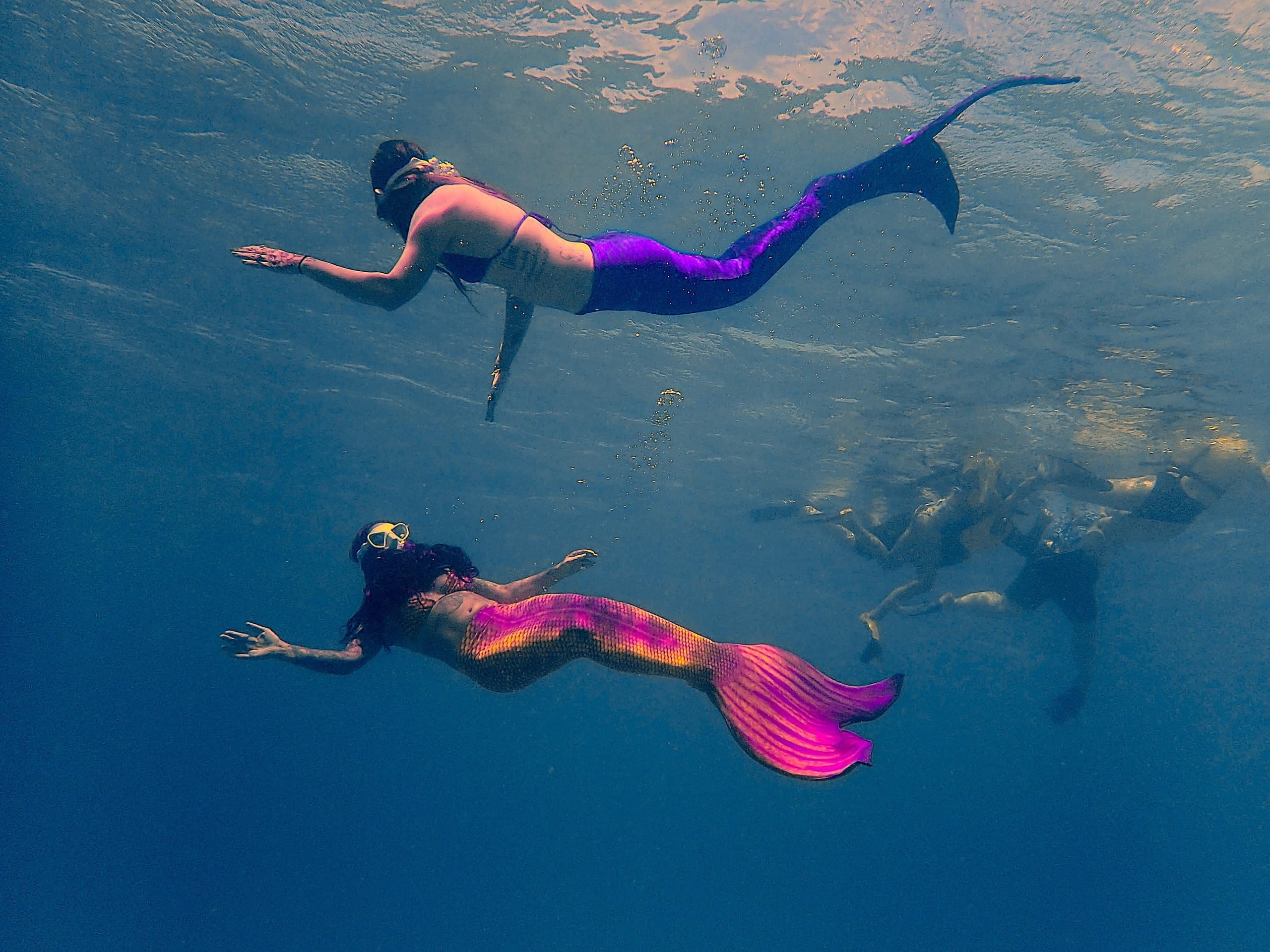 Underwater mermaid swim performance beside snorkelers in open ocean