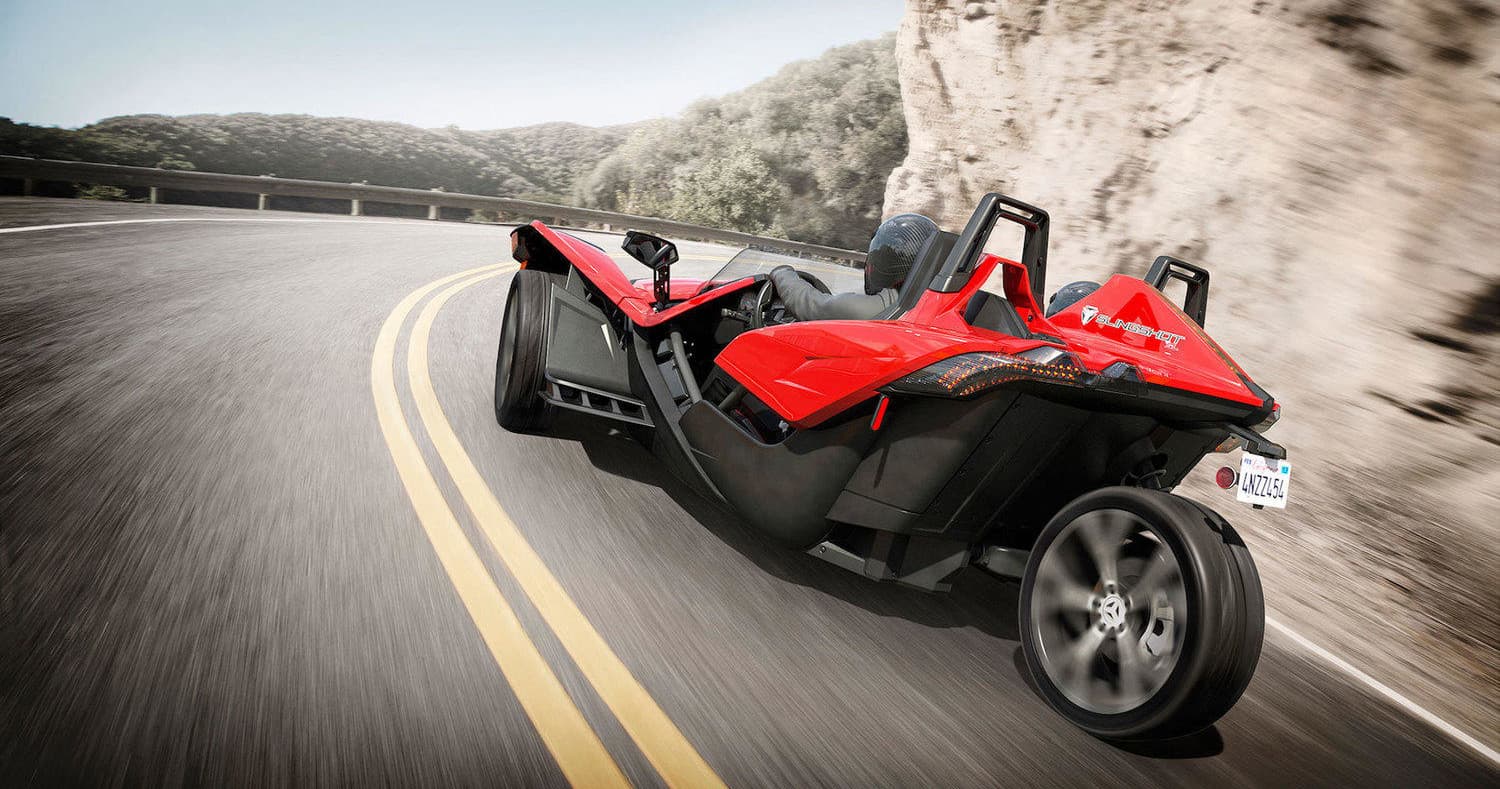 Red Slingshot speeding along winding cliffside highway