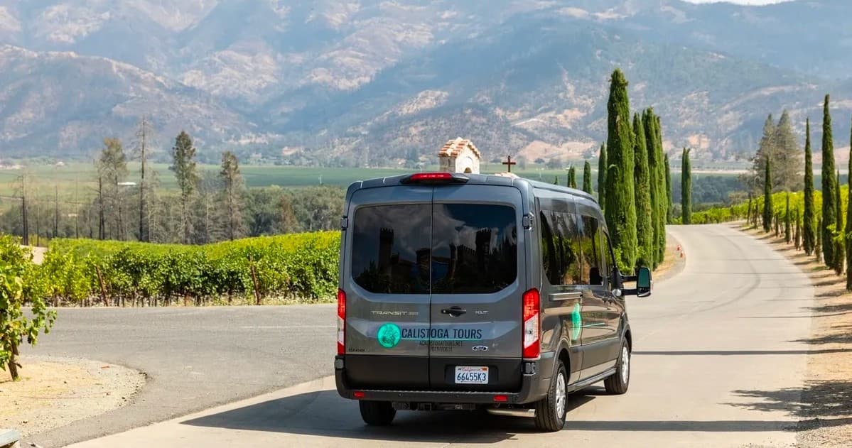 Tour van driving along vineyard-lined road in Napa Valley scenery