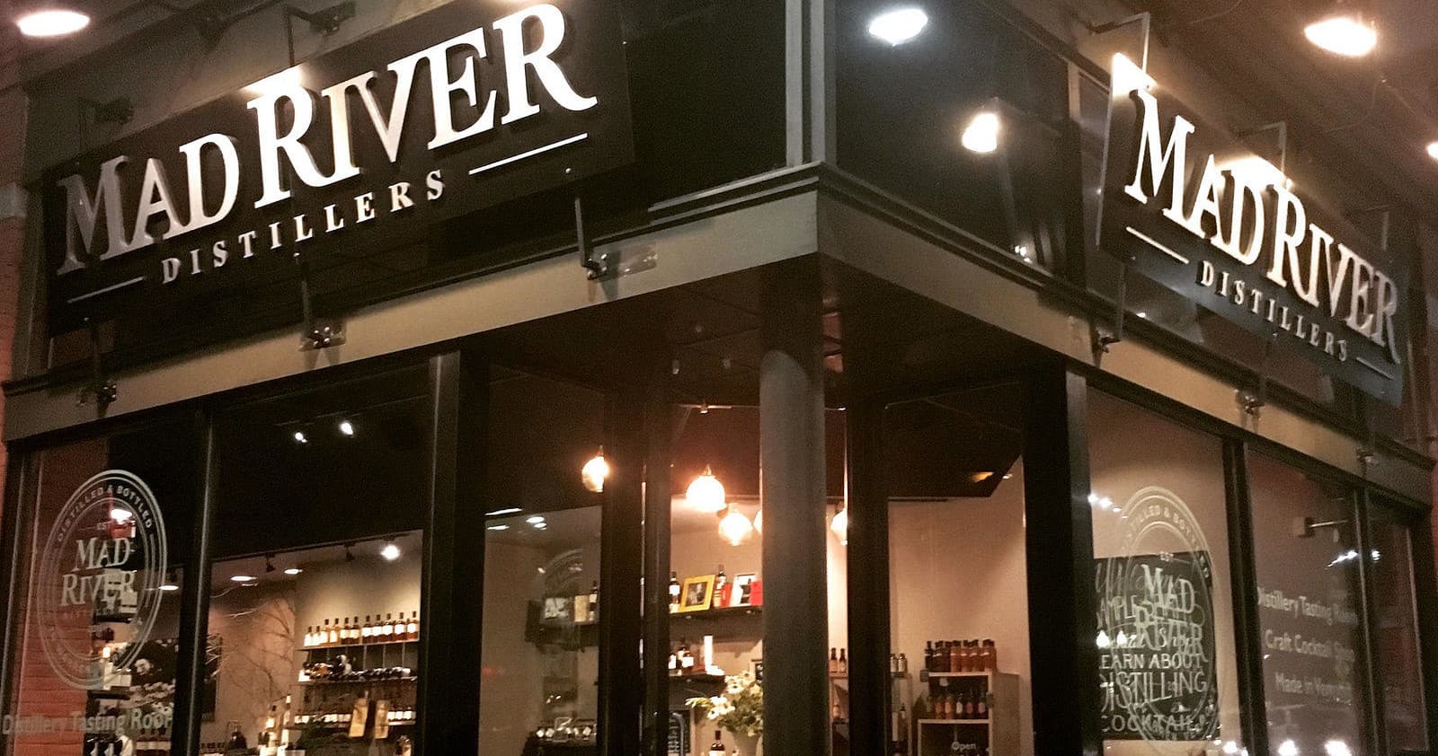 Mad River Distillers storefront at night on urban street