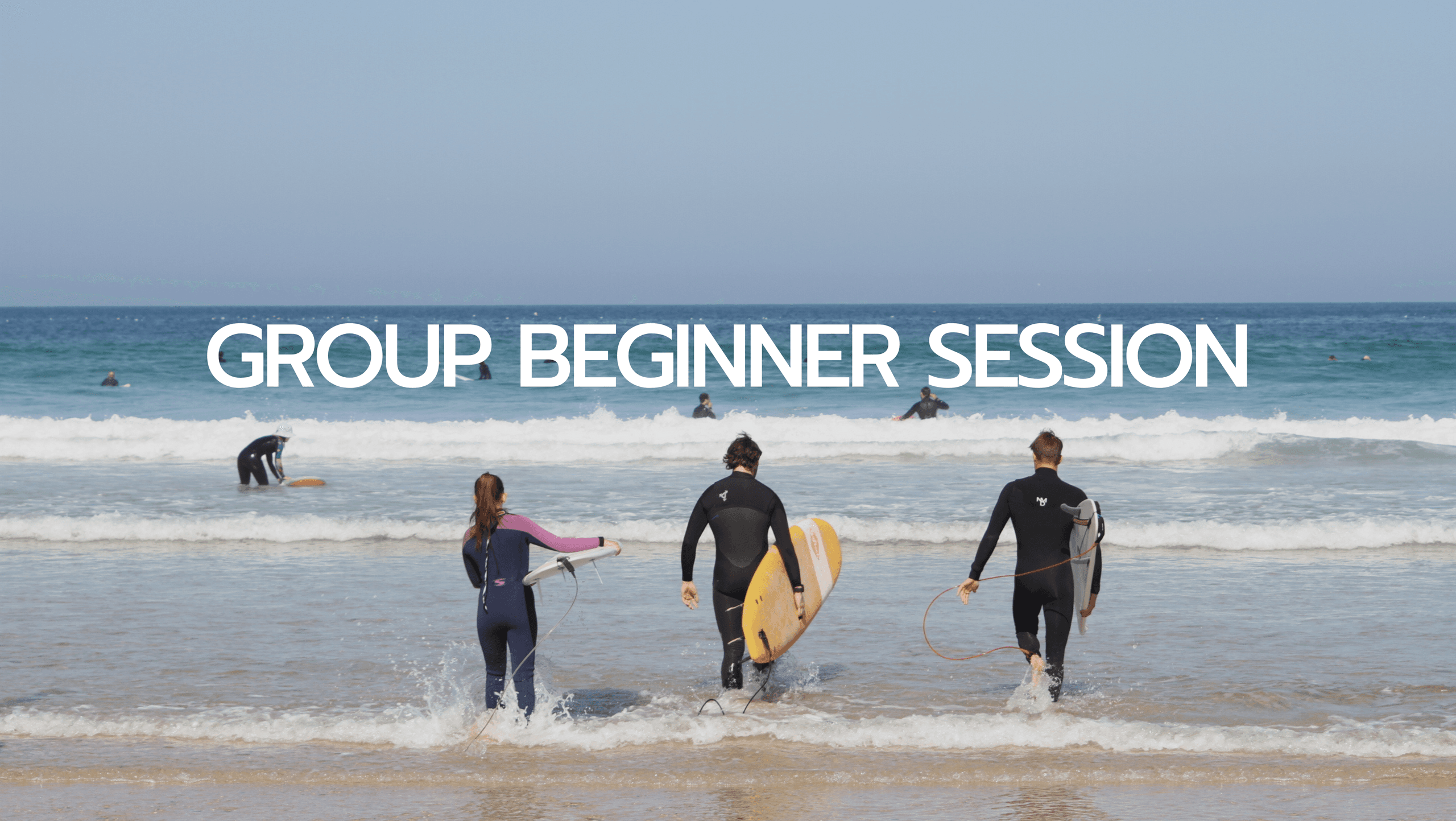 Group of surfers walking into ocean waves on sandy beach, beginner surf session