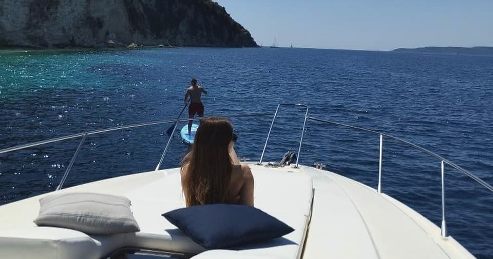 Passenger relaxing on bow with open sea views, coastal cruising