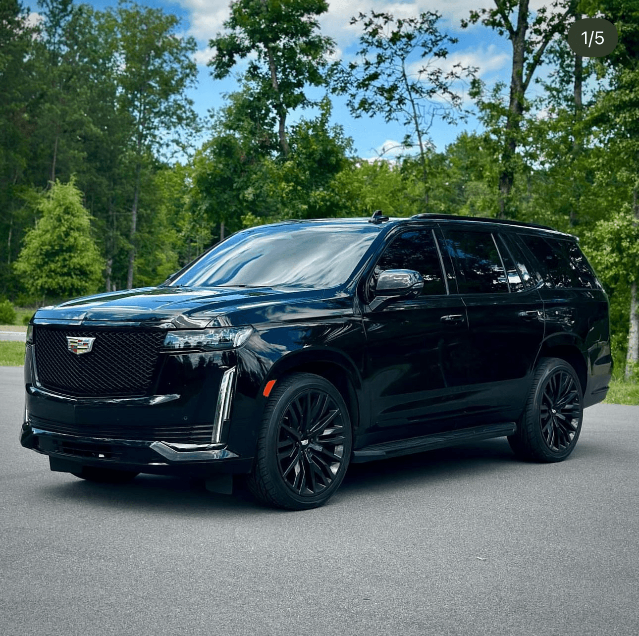 Black Cadillac Escalade parked on tree-lined road for scenic drive