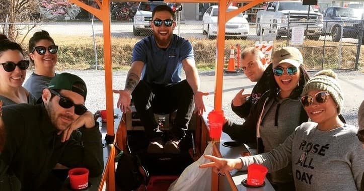 Group smiling on multi-seat pedal bike tour through city