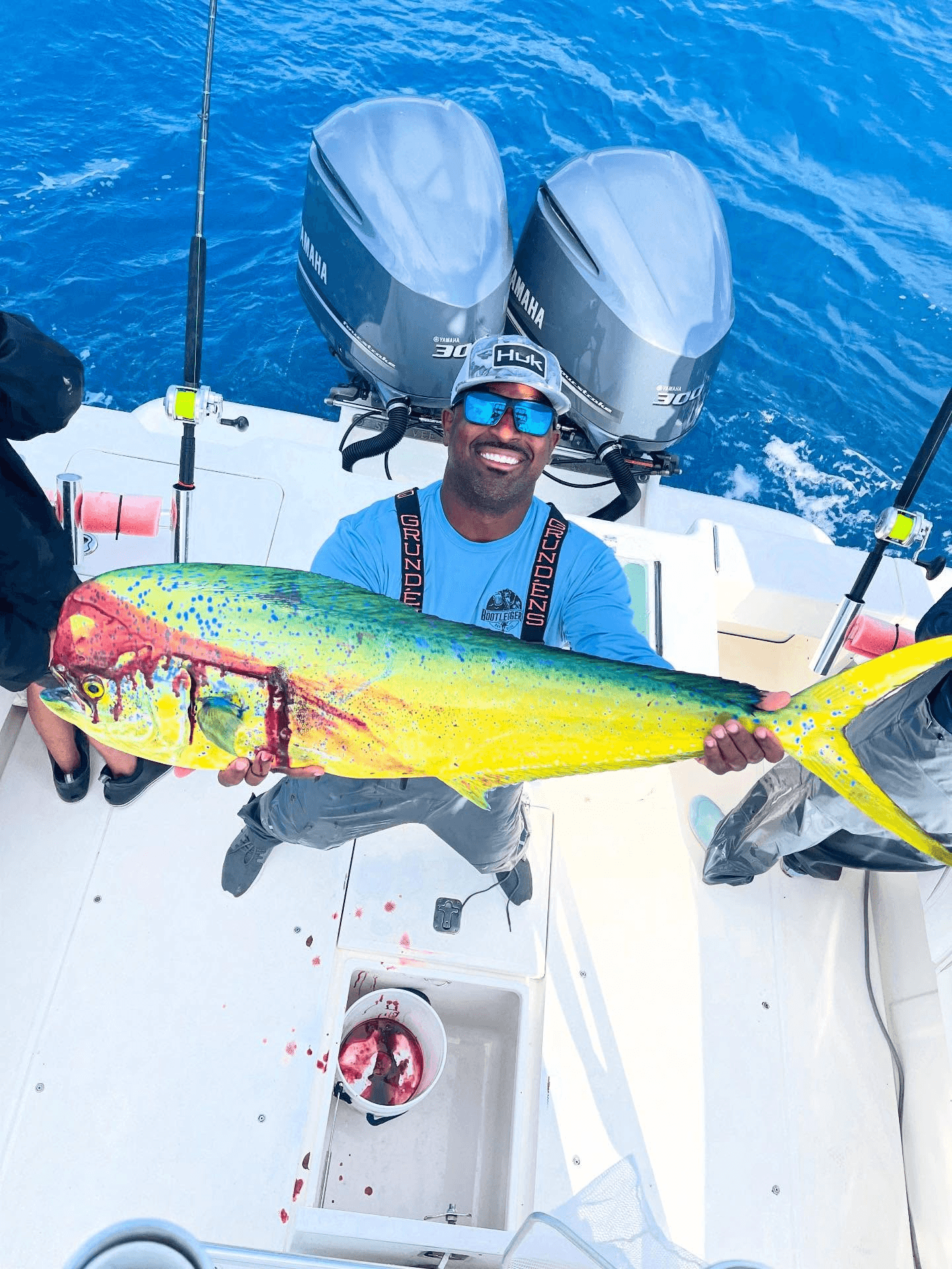 Fisherman holding mahi-mahi on sportfishing boat deck at sea