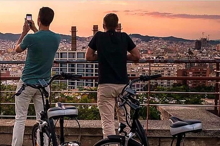Cyclists overlooking city skyline at sunset on e-bike tour