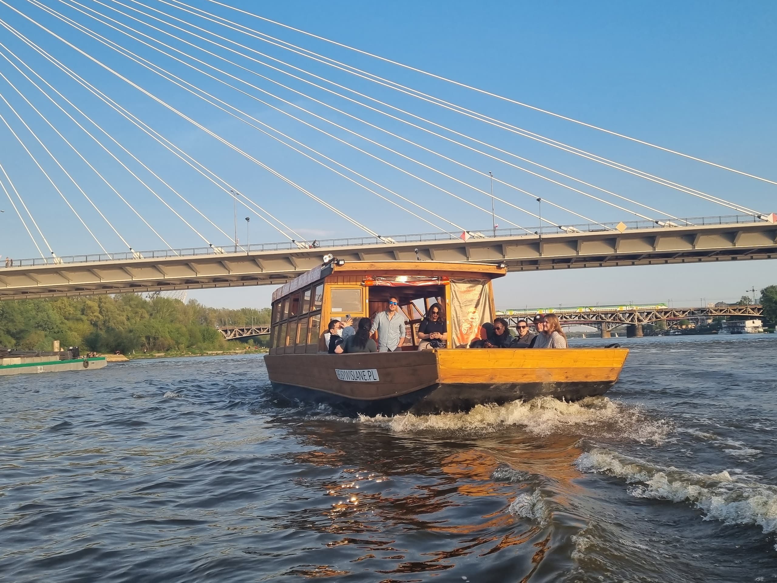 Sightseeing boat cruising under modern bridge on Vistula