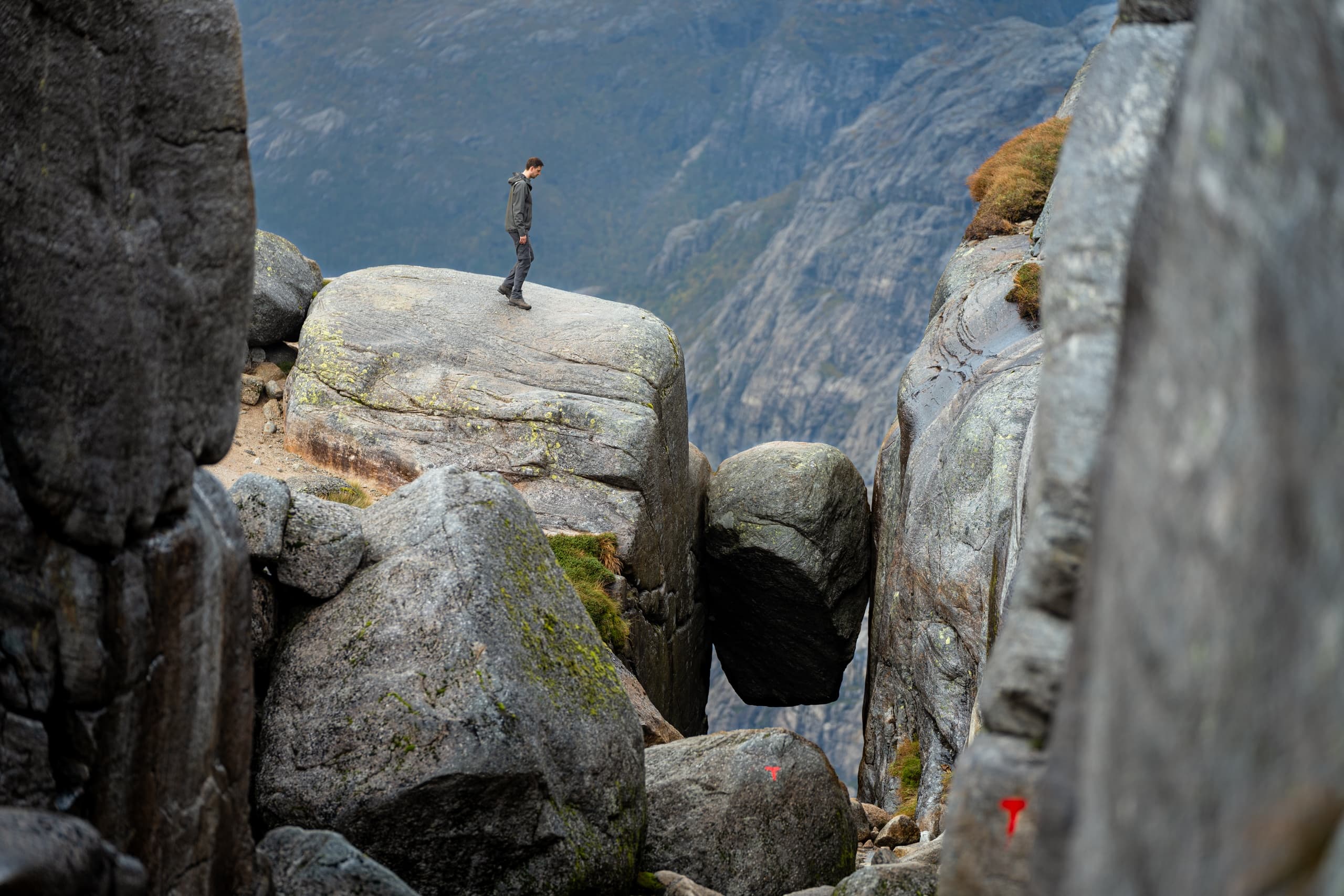 Hiker standing among huge boulders on rocky Norwegian ridge