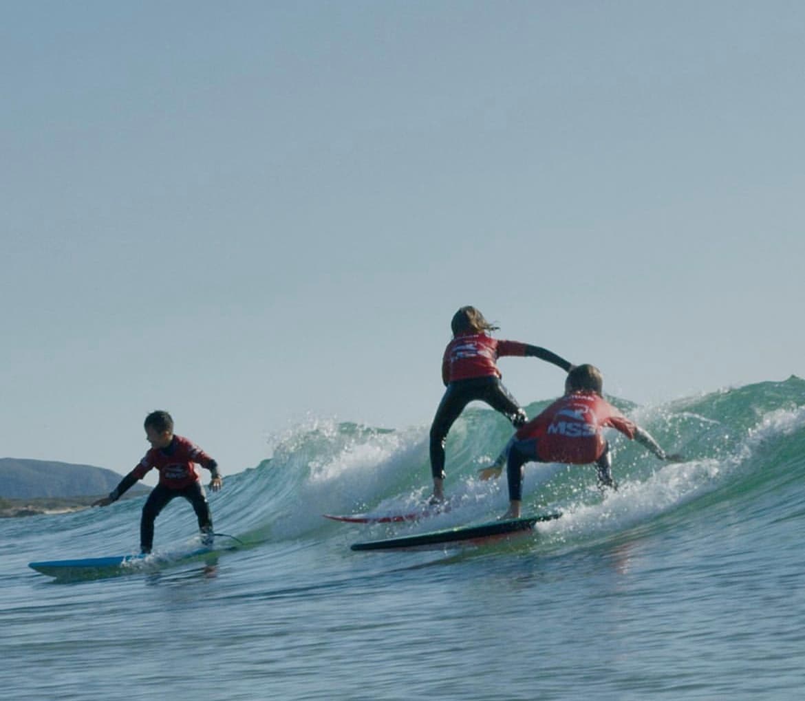 Surfers carving medium waves on a sunny coastal beach