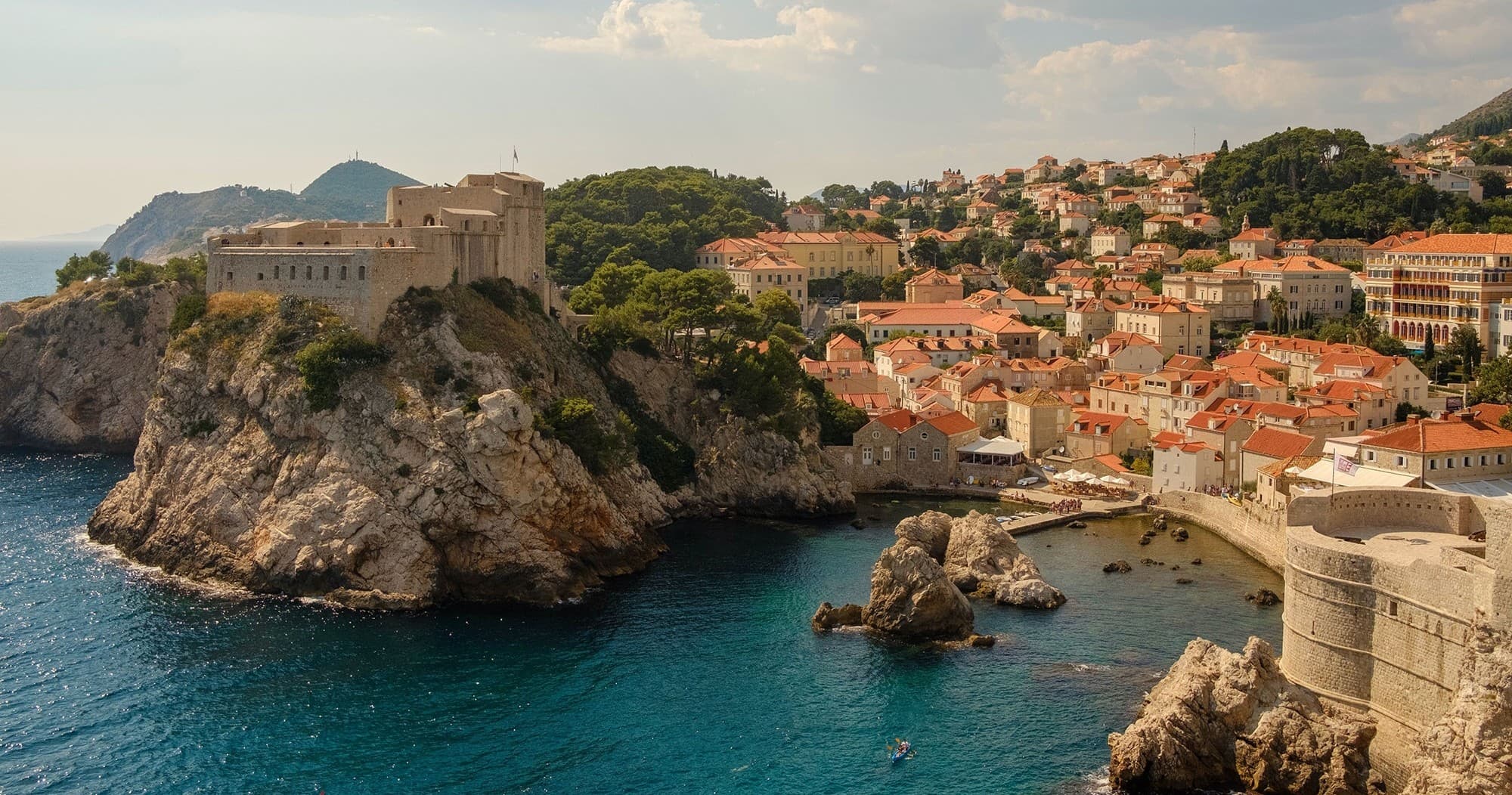Coastal boat cruising past historic Dubrovnik walls on Adriatic