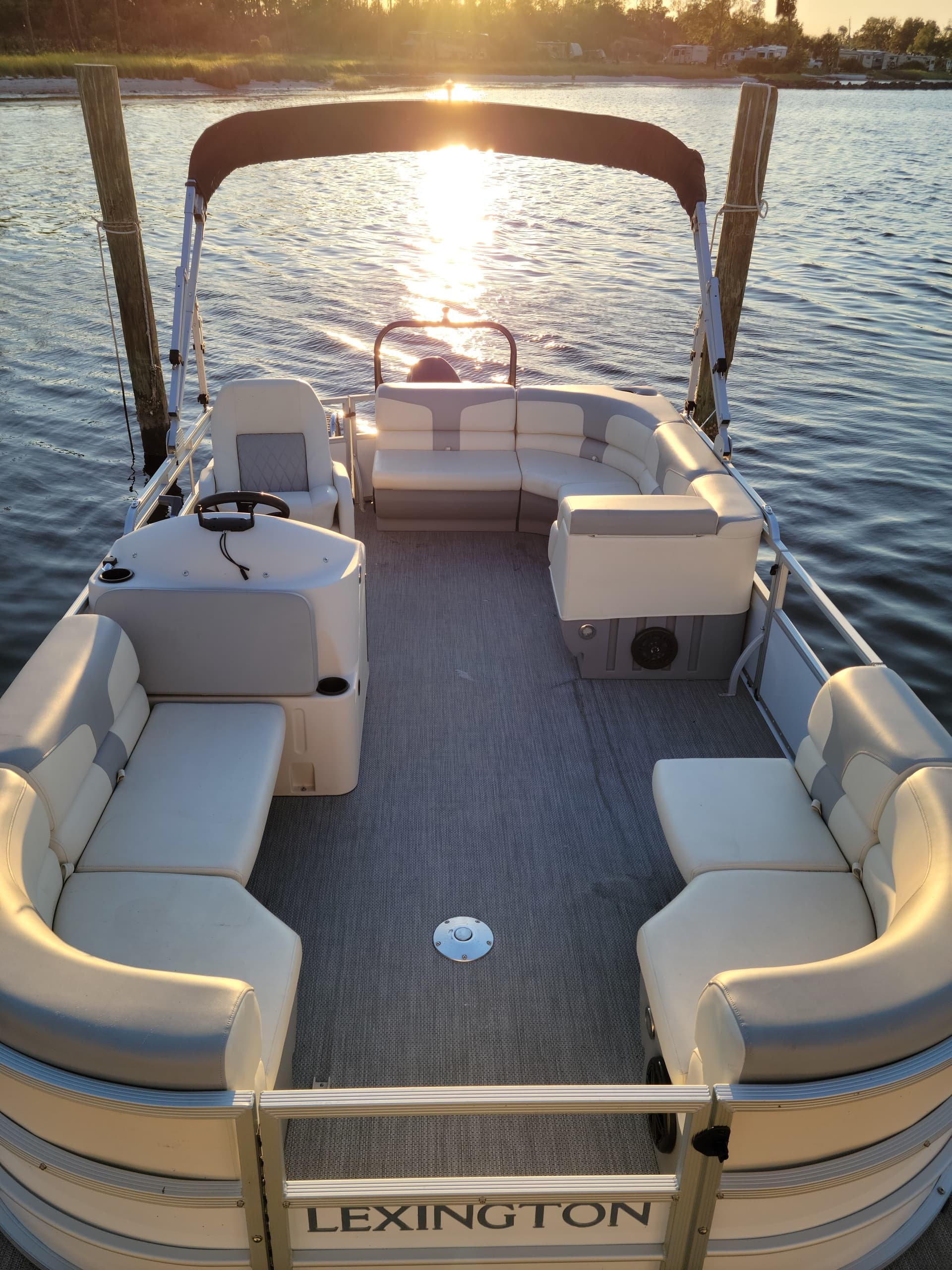 Sunlit pontoon boat interior facing sunset on calm bay