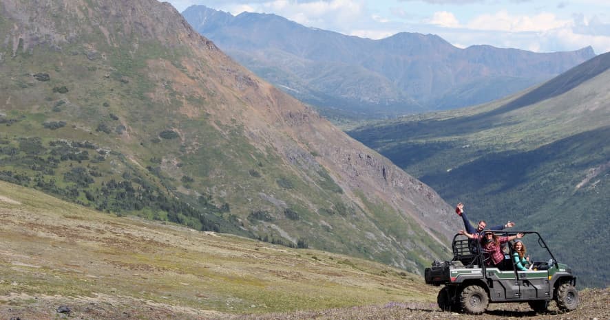 Off-road jeep driving across alpine tundra with mountain views