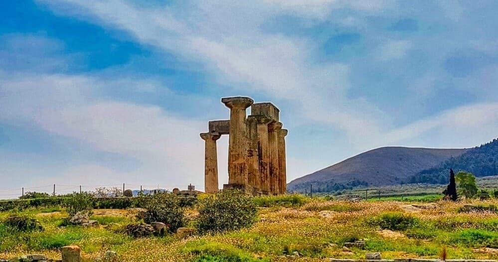 Stone temple ruins amid wild coastal meadow under blue sky