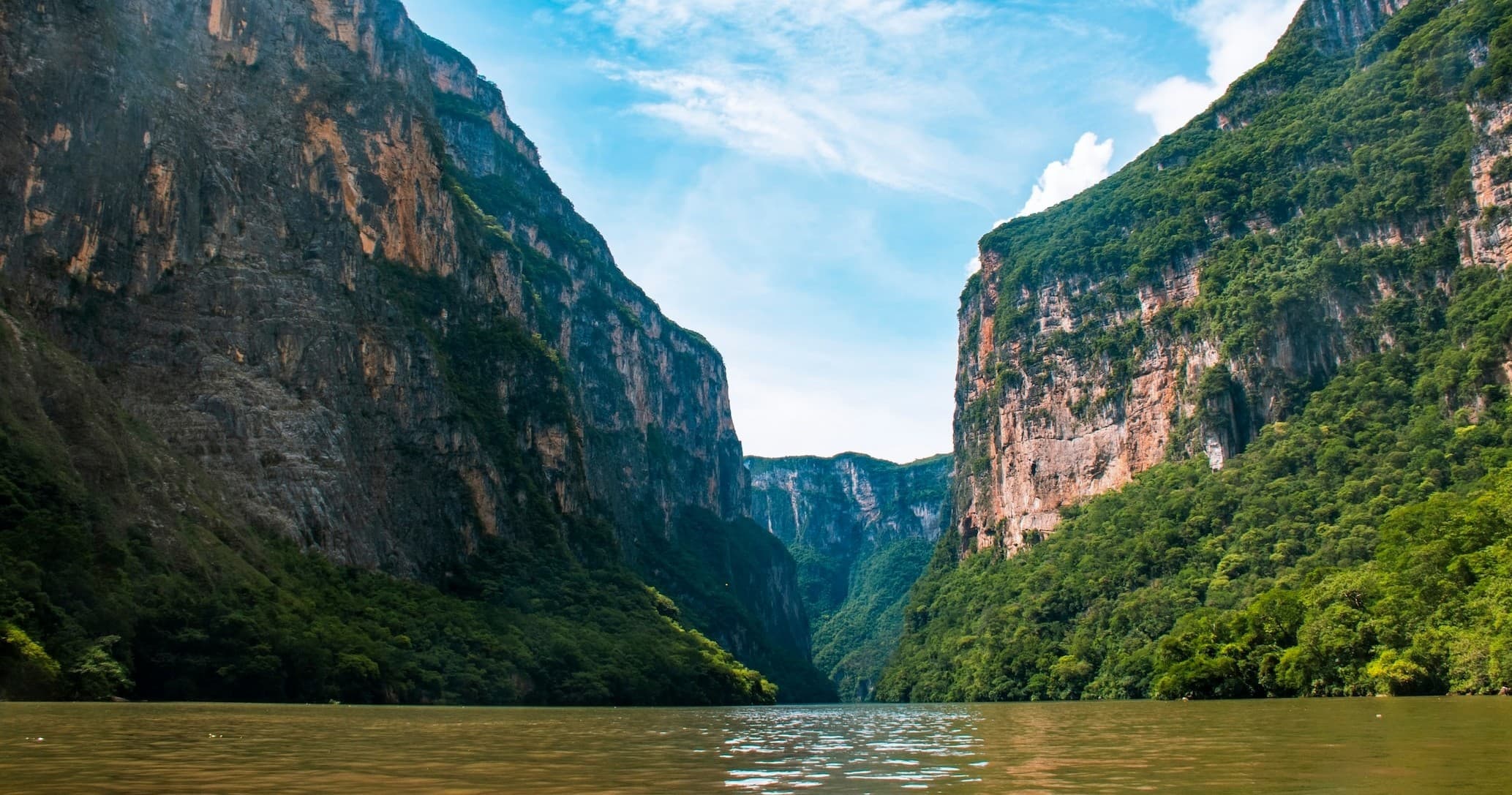 River canyon boating through dramatic green cliffs, scenic gorge