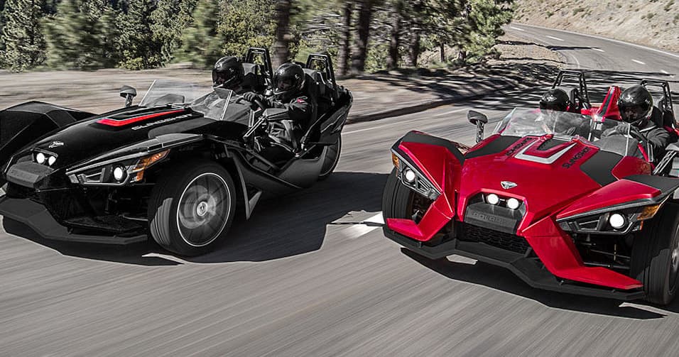 Two three-wheeler riders cruising scenic forested highway