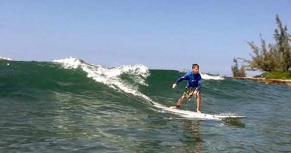 Surfer riding a breaking wave near tropical shoreline