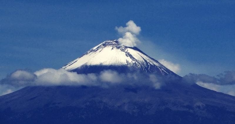Snow-capped volcano rising above valley at golden sunrise