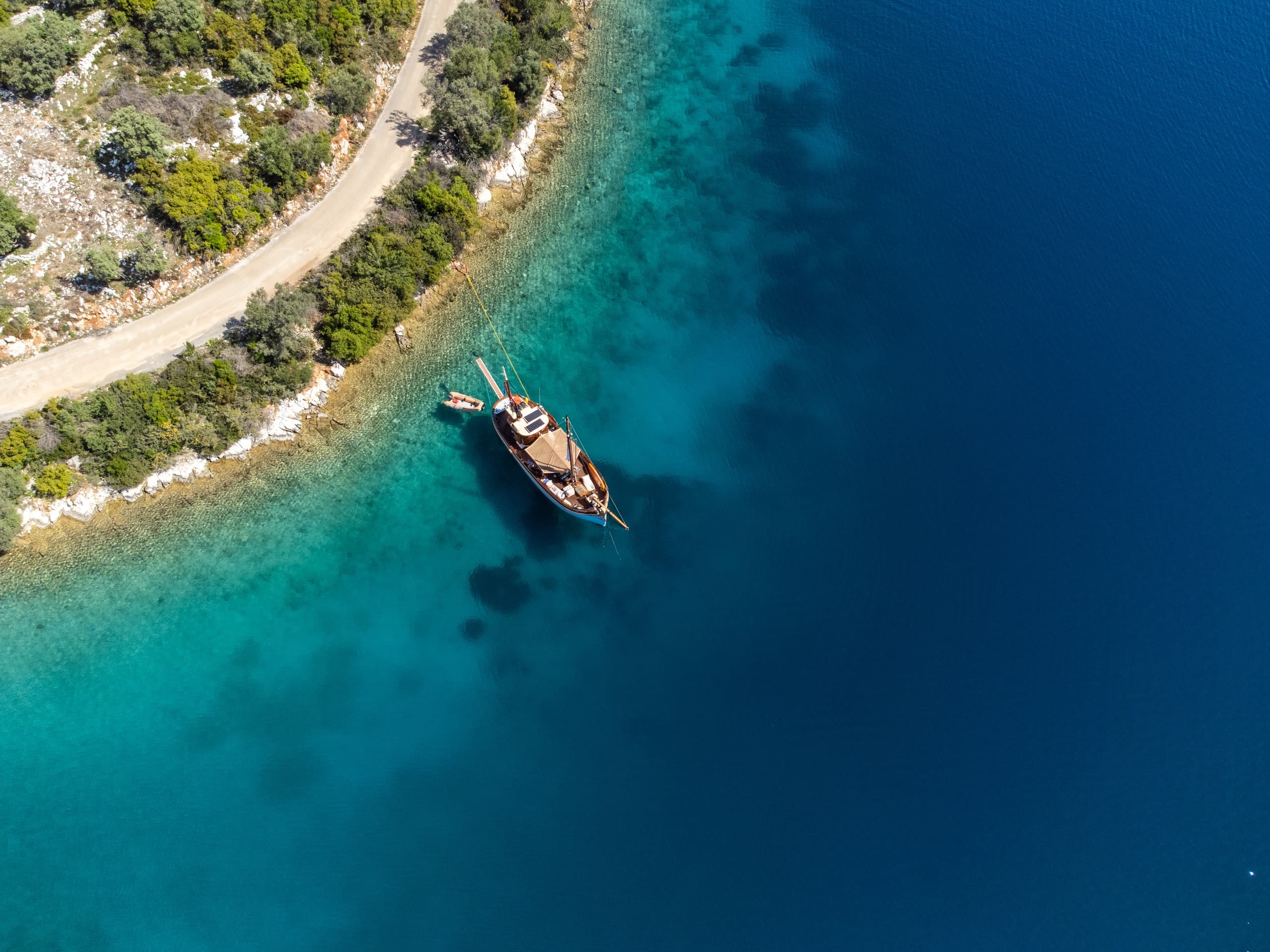 Aerial view of wooden boat moored along rocky Ionian coastline