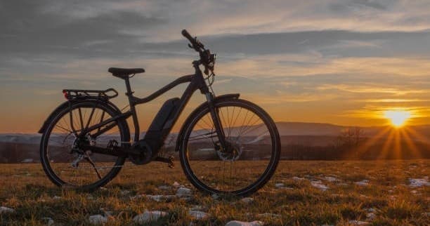 E-bike silhouette cycling at sunset across open grassland