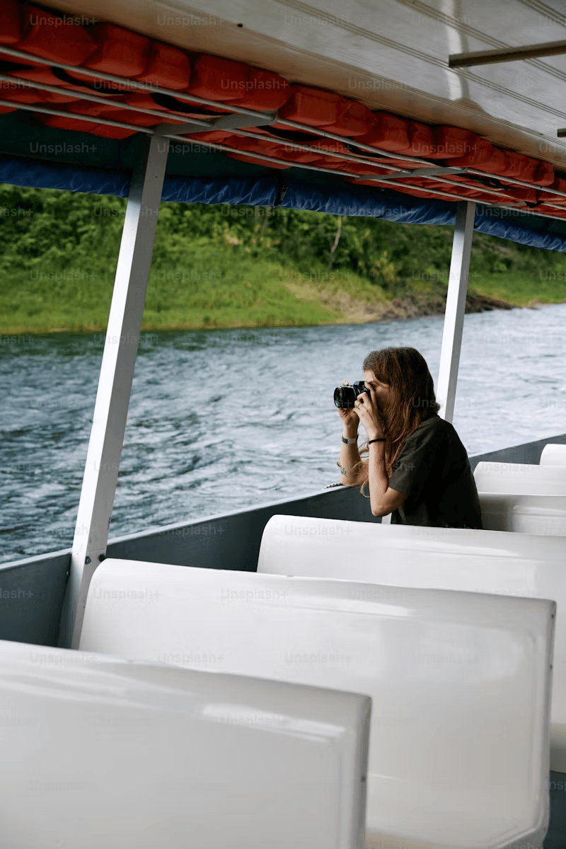 Photographer on boat taking photos of river shoreline landscape