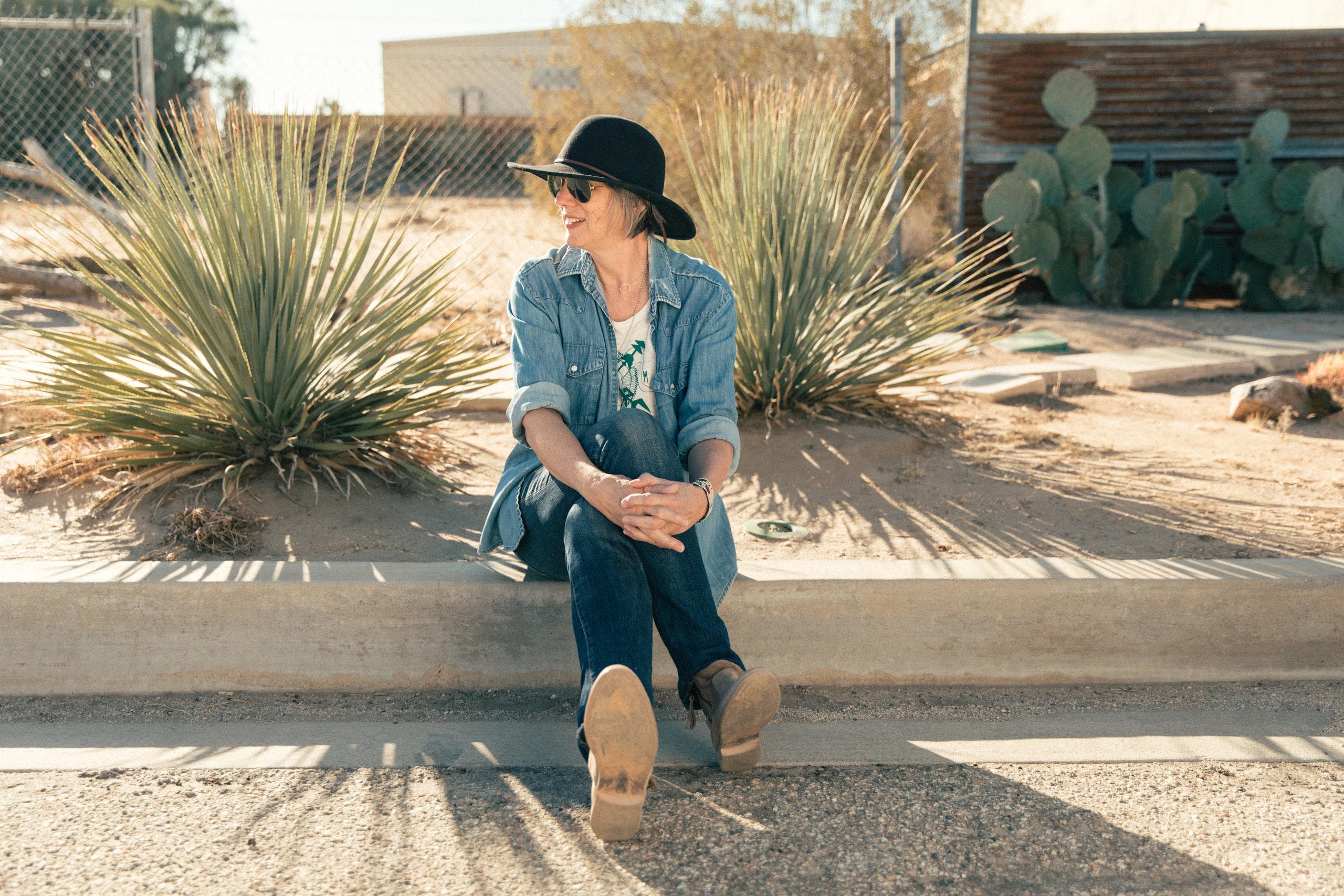 Artist sitting outdoors by desert plants enjoying plein air painting