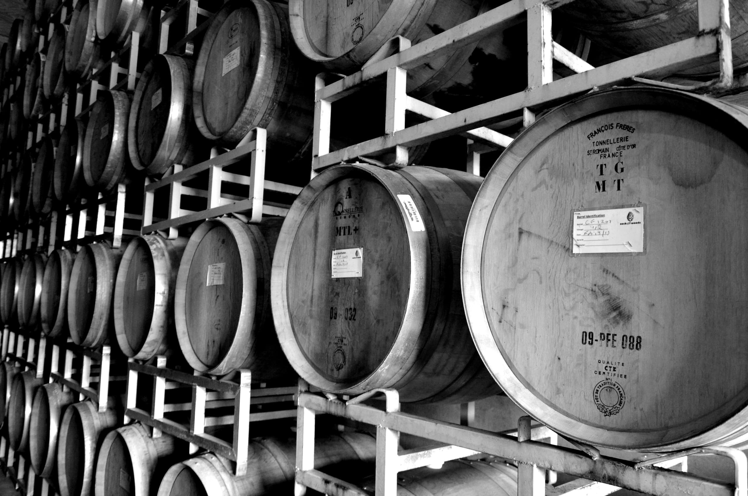 Stacked oak wine barrels in winery cellar racked for aging