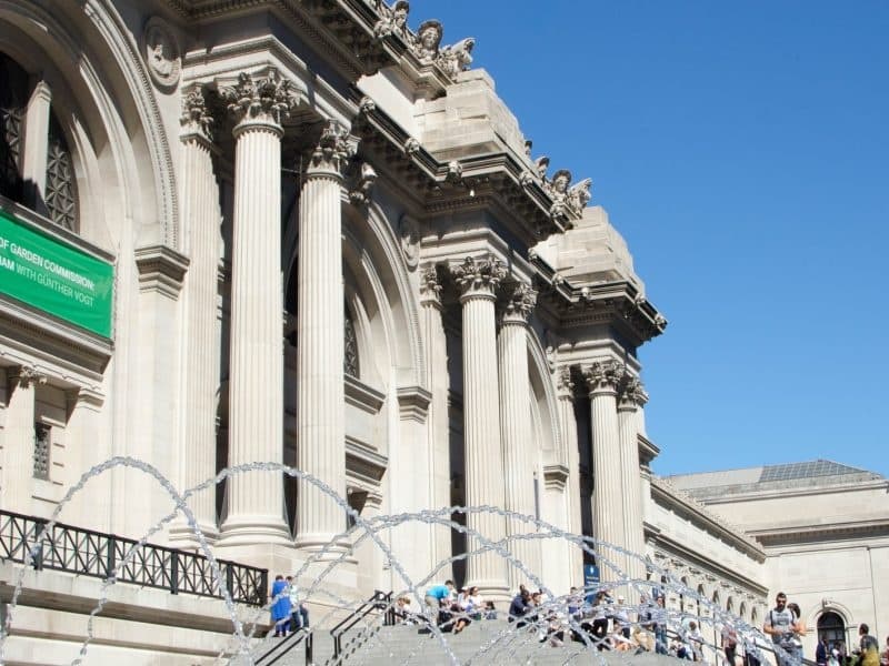 Visitors ascending grand museum steps at classical exterior