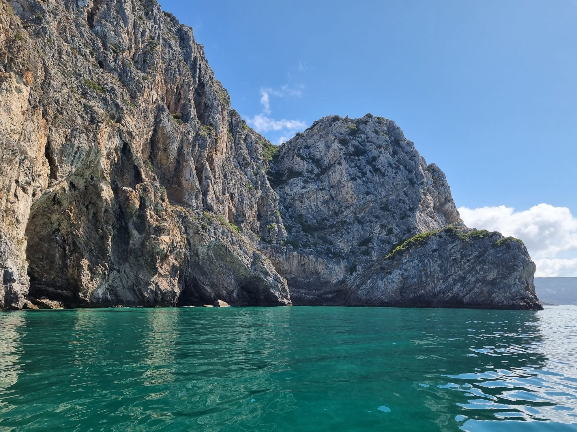 Clear water at towering coastal cliffs on a sunny boat tour