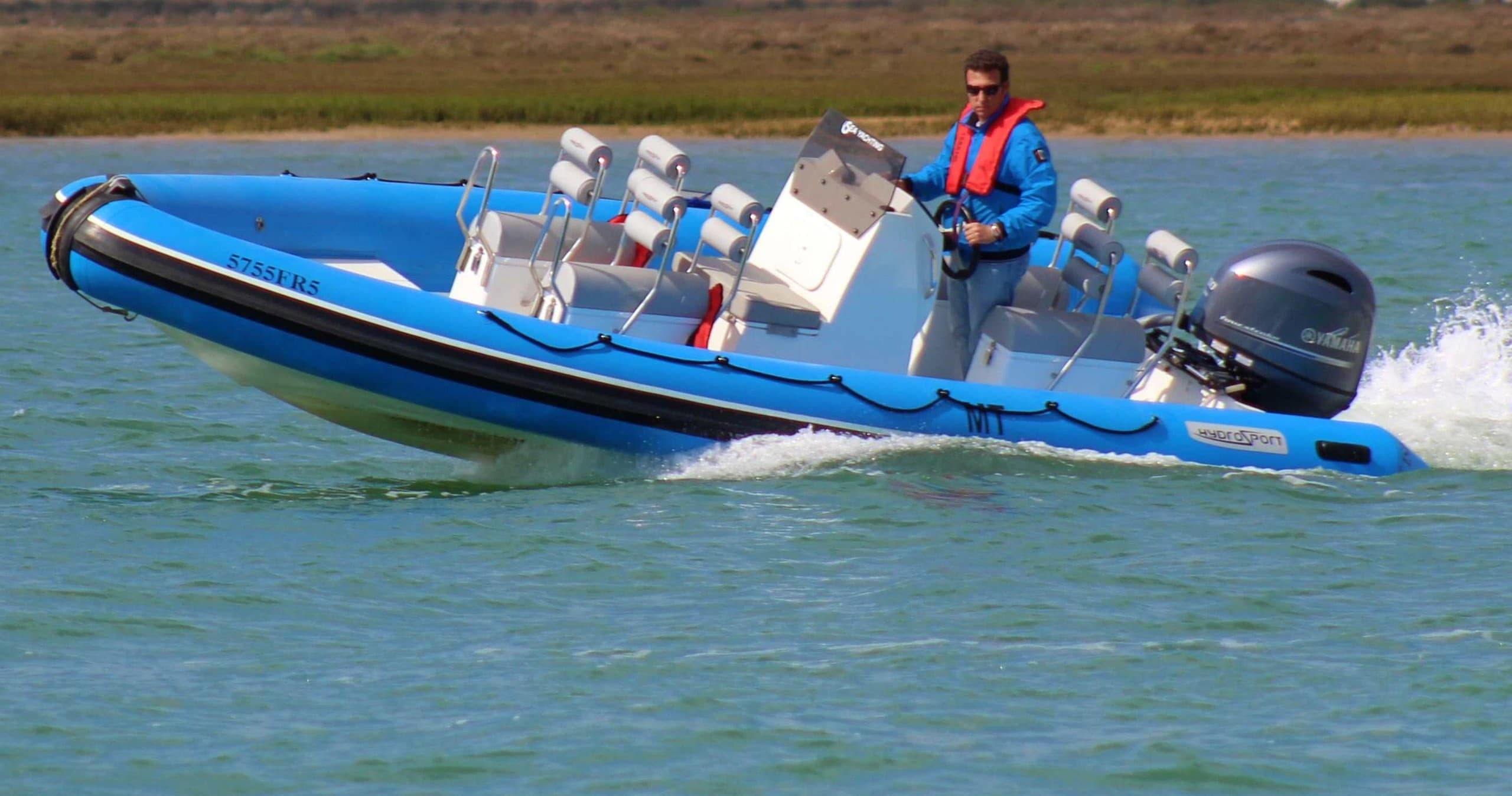 Rigid inflatable boat speeding on coastal waters with crew aboard