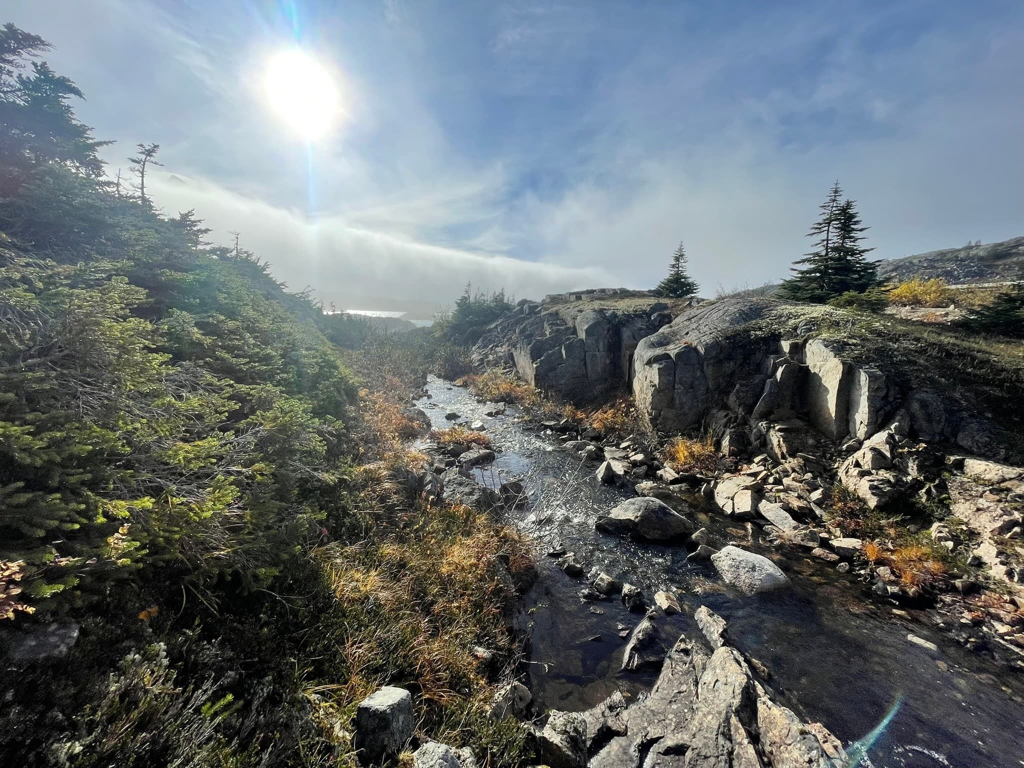Rocky alpine river canyon with sunlit hiking trail in Alaska
