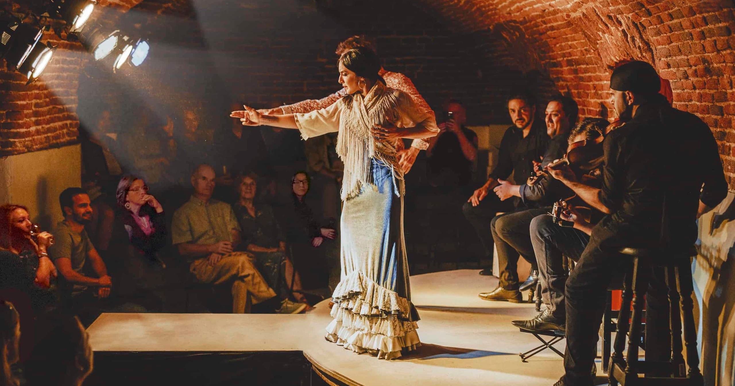 Flamenco dancer performing on small stage in brick cellar