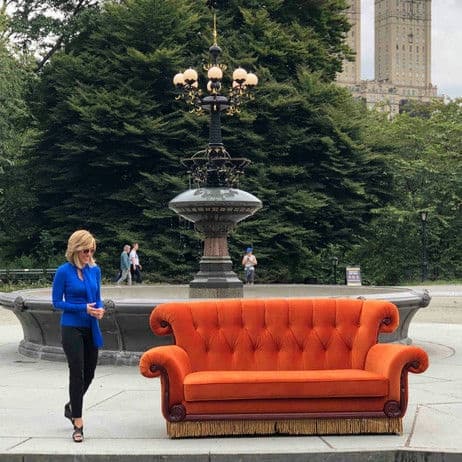 Bright orange sofa staged by park fountain for a photo shoot
