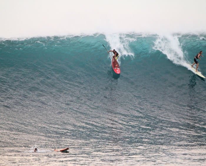 Surfer dropping into a massive blue ocean wave at reef break