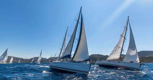 Multiple sailboats racing together on choppy coastal waters