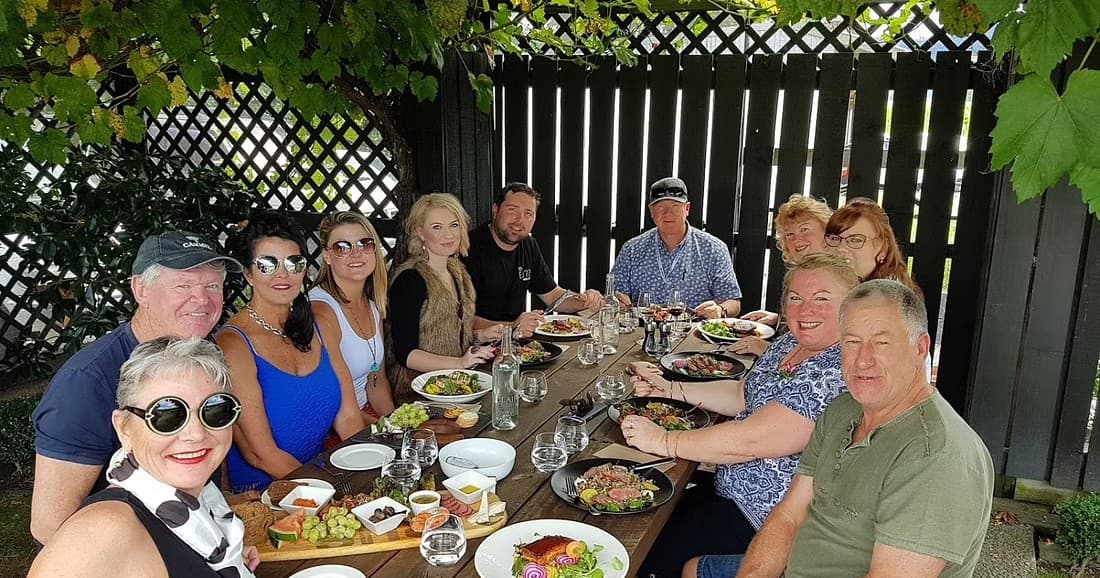 Outdoor winery lunch and group tasting under vine-covered pergola