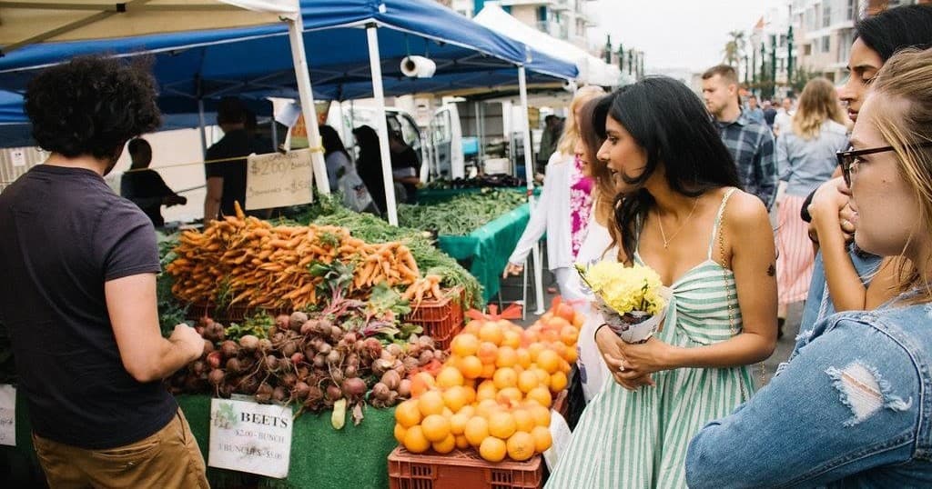 Shoppers browsing fresh produce at outdoor farmers market