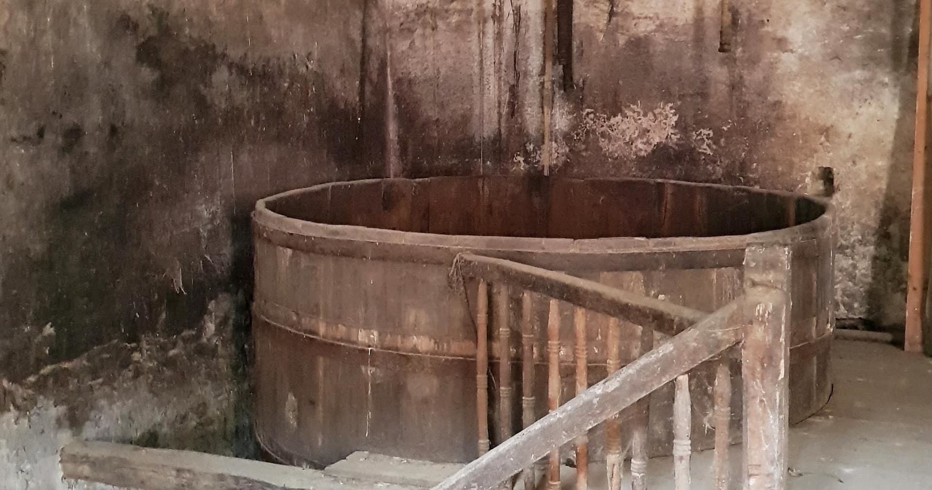Historic wooden wine vat inside a rustic cellar fermentation room
