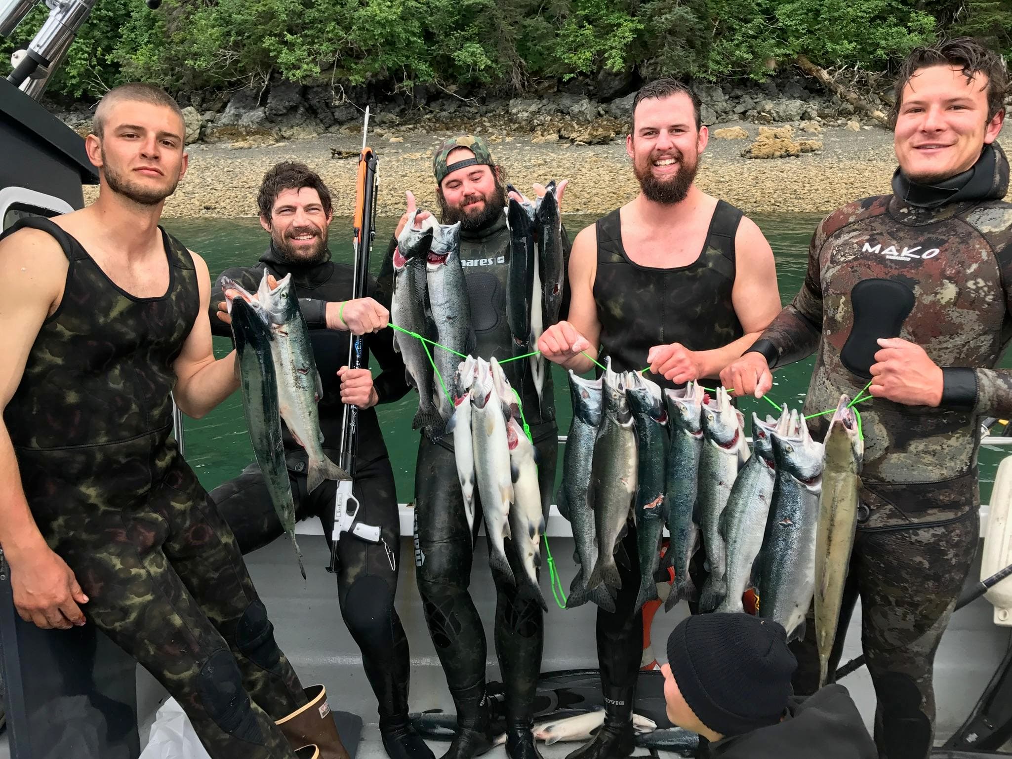 Anglers holding giant halibut on boat against mountain backdrop